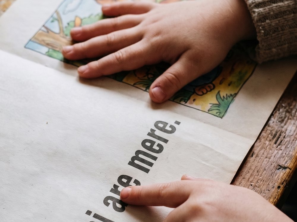 Copilul acoperă desenul și citește cu degetul pe litere